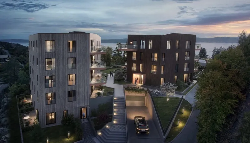 Fjordhøyden: to boligblokker med trekledning i skumringen, med utsikt mot fjorden