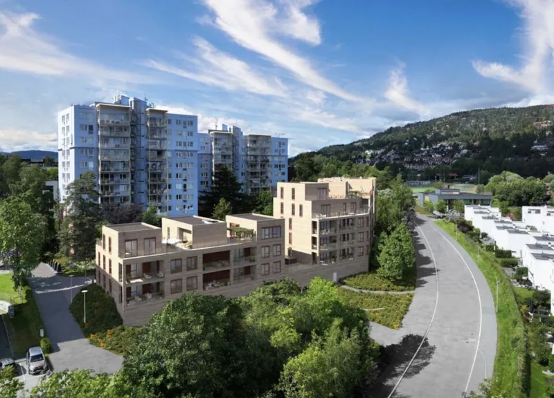 Landingsveien 14: boligbygg med lys fasade foran høyblokker, med skogkledd ås i bakgrunnen