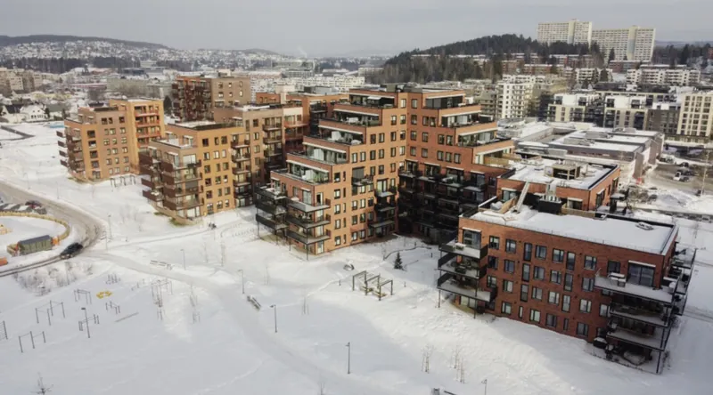 SkårerByen byggetrinn 3–4: boligblokker i rød og oransje tegl i et snødekt landskap, sett ovenfra