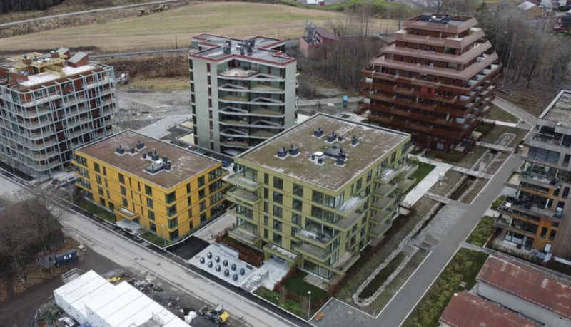 Magasinparken: boligbygg med gul og grønn fasade og flere høyhus i bakgrunnen, sett ovenfra